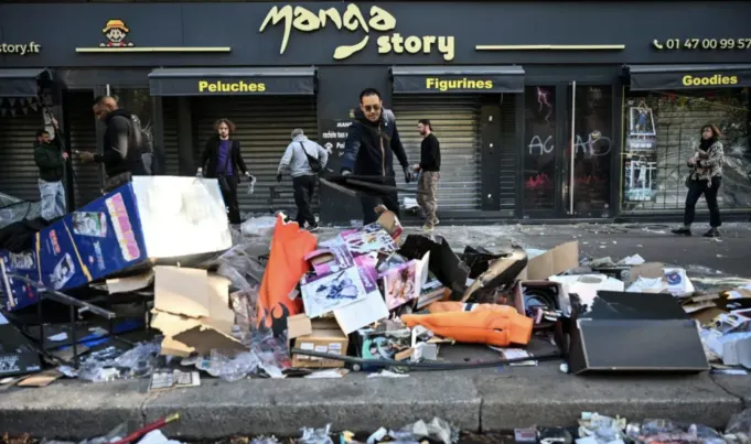 Seorang pemilik toko membersihkan bagian depan tokonya yang rusak akibat unjuk rasa menentang tingginya biaya hidup di Paris, Prancis, Minggu (18/10/2026). Tripodnews/AFP